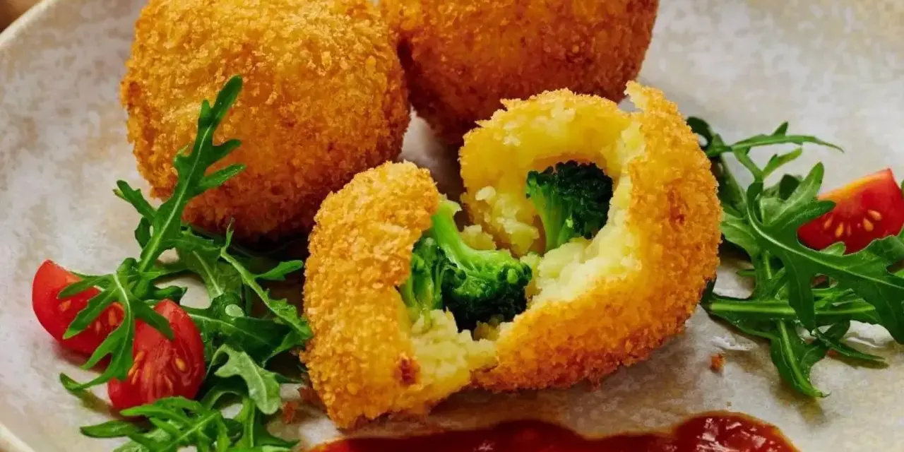 Chrupiące kulki ziemniaczane w panko z brokułami w środku, podane z rukolą i pomidorkami.