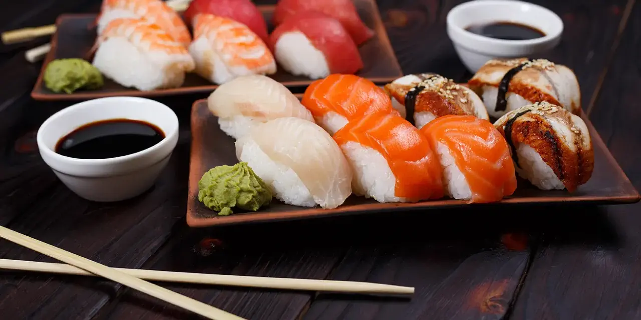Wyśmienite japońskie sushi: nigiri z łososiem, rybą maślaną i krewetką, podane z wasabi i sosem sojowym.