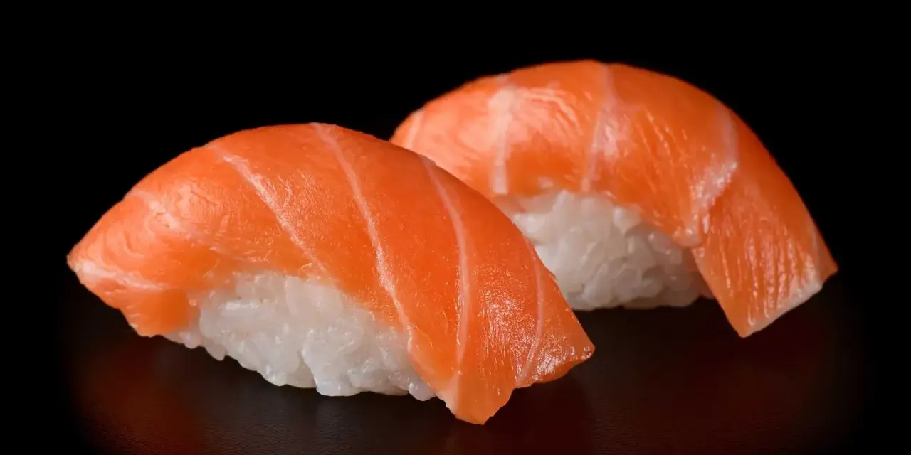 Dwa kawałki sushi z łososiem, idealna ryba do sushi, na czarnym tle.