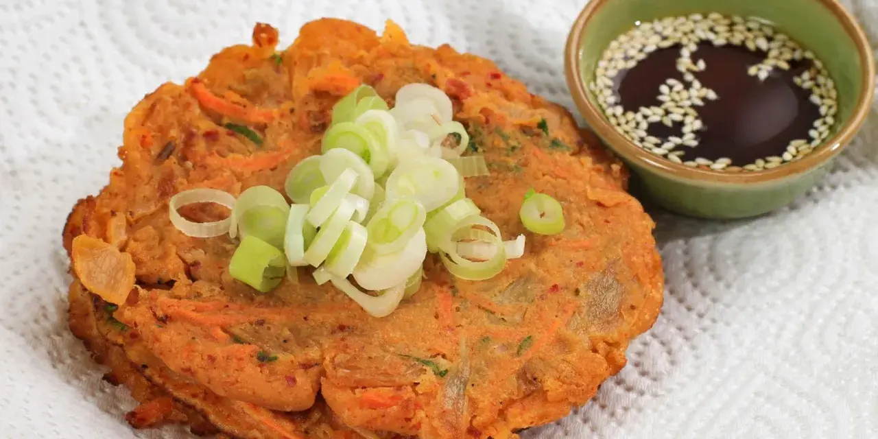 Chrupiące placki z kimchi, posypane szczypiorkiem, obok miseczki z sosem sezamowym. Idealne na przekąskę.