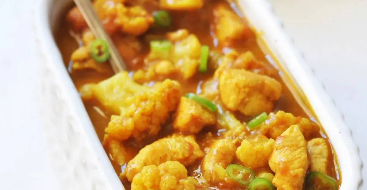 Aromatyczne curry z kurczakiem i kalafiorem w kremowym sosie, posypane zieloną papryczką chili.