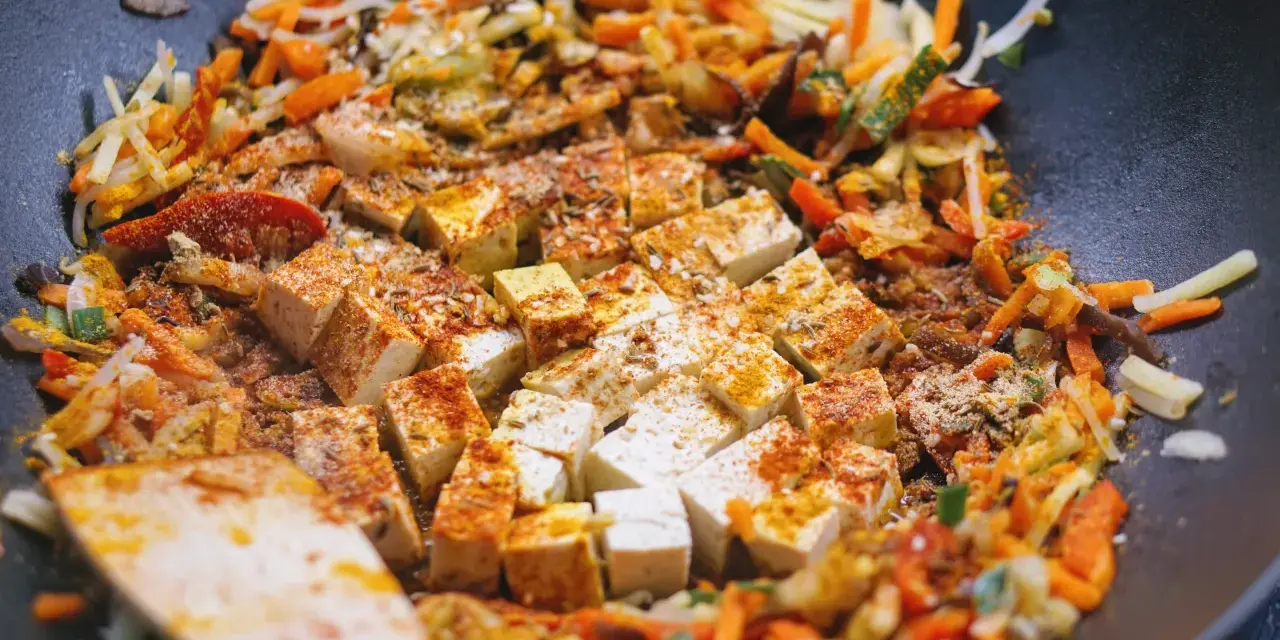Smażone warzywa po chińsku z tofu i ryżem, doprawione kurkumą i papryką, gotowe do podania.
