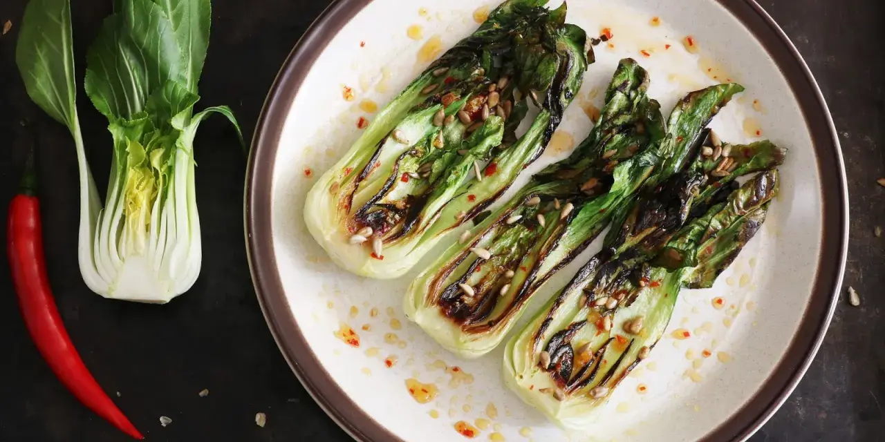 Grillowany pak choi z nasionami słonecznika i papryczką chili na talerzu.