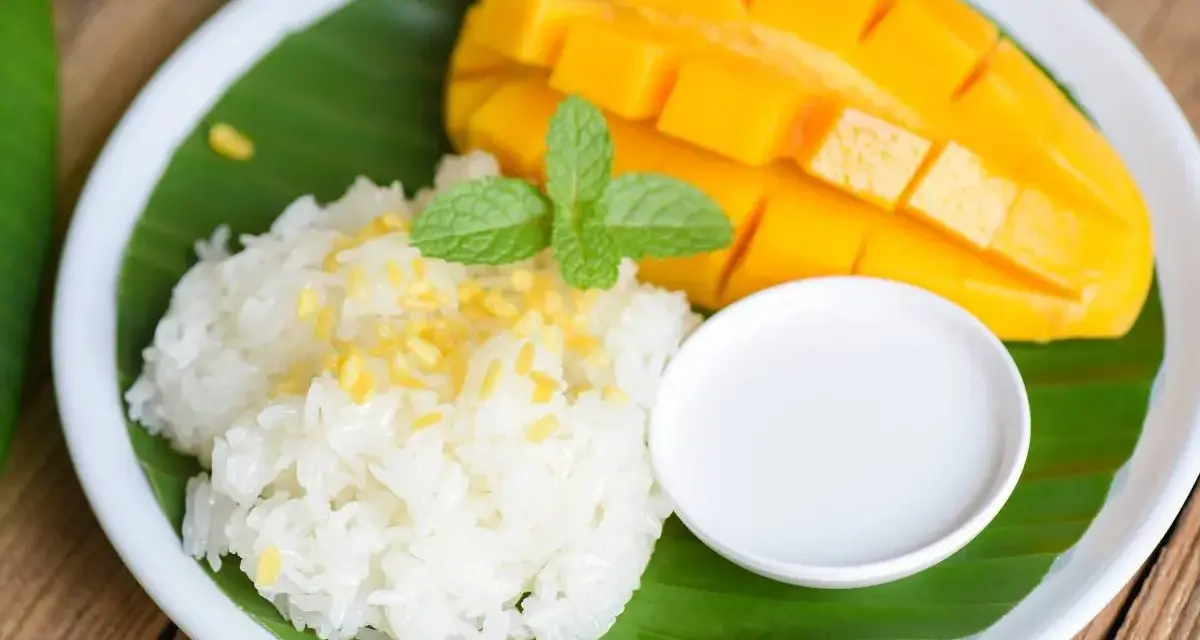 Pyszny mango sticky rice: ryż kleisty z kawałkami mango, polany mleczkiem kokosowym, udekorowany miętą.