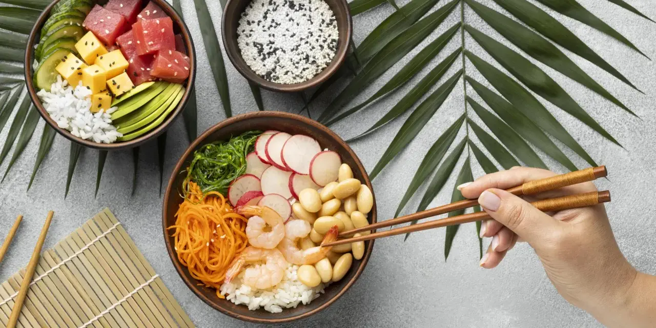 Dwie miski z pysznym sushi: jedna z tuńczykiem, awokado i ogórkiem, druga z krewetkami, fasolką i warzywami.