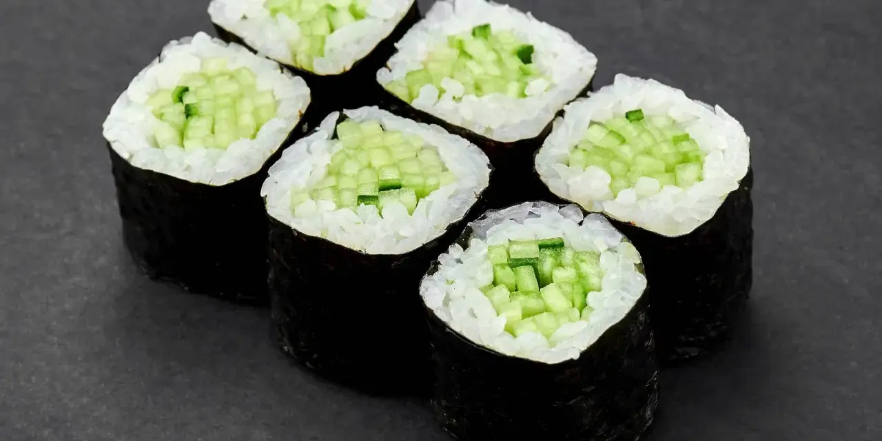 Sześć kawałków sushi z ogórkiem, ułożonych na ciemnym tle.