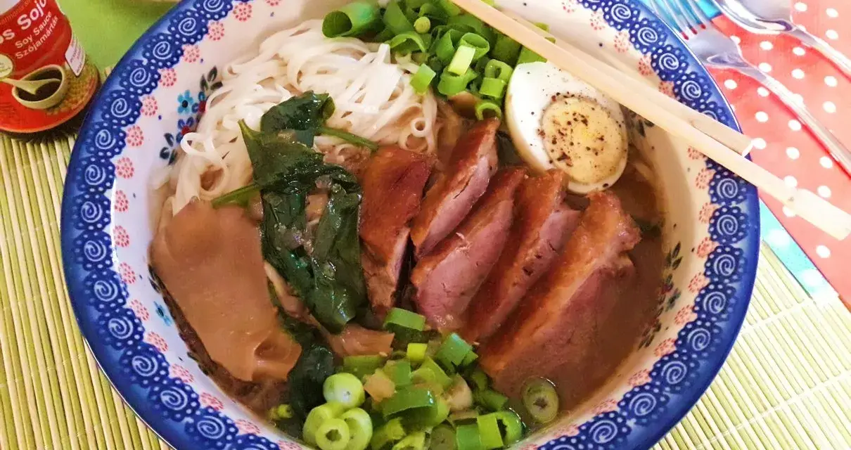 Pyszny ramen z kaczki z makaronem, jajkiem, szpinakiem i szczypiorkiem.