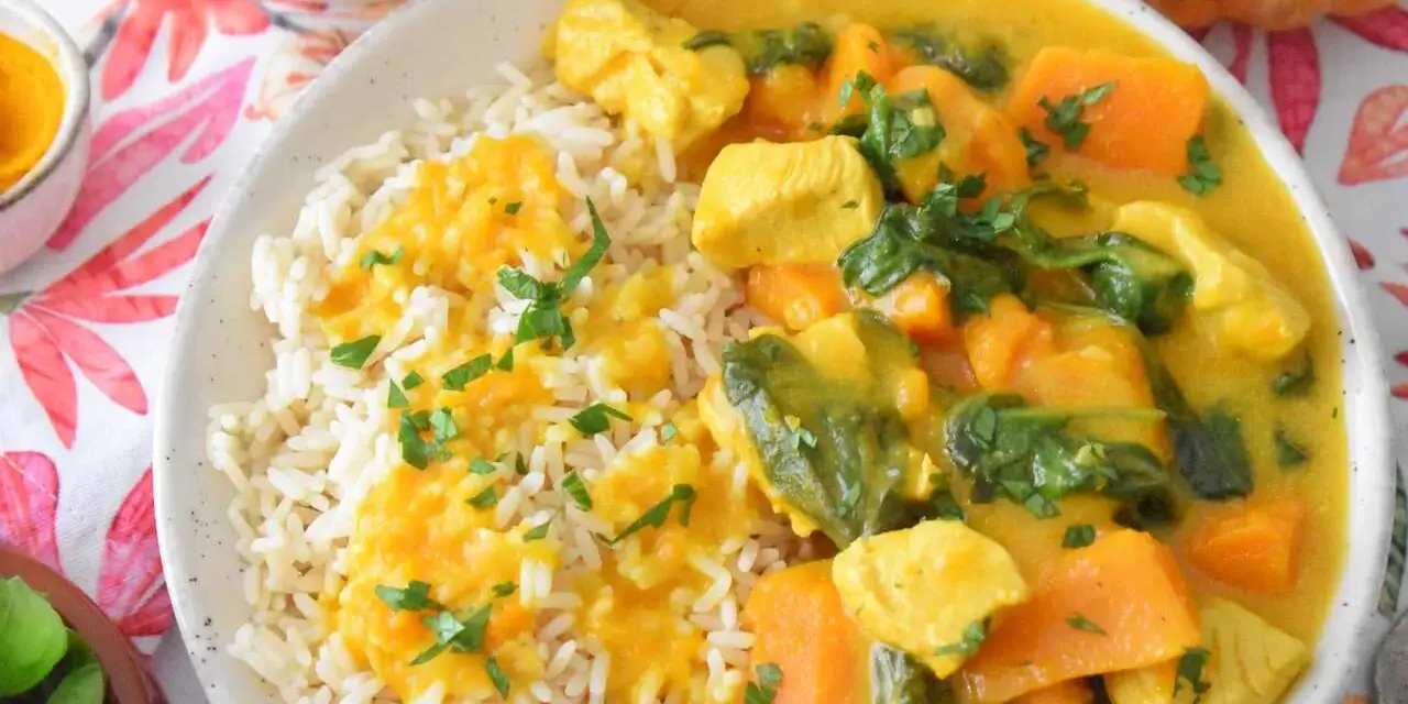 Aromatyczny kurczak curry z dynią i mlekiem kokosowym, podany z ryżem i posypany natką pietruszki.