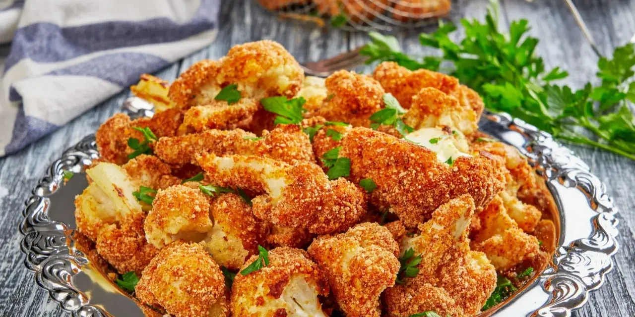 Chrupiący kalafior w panko, podany na ozdobnej tacy, posypany świeżą natką pietruszki. Idealna przekąska!
