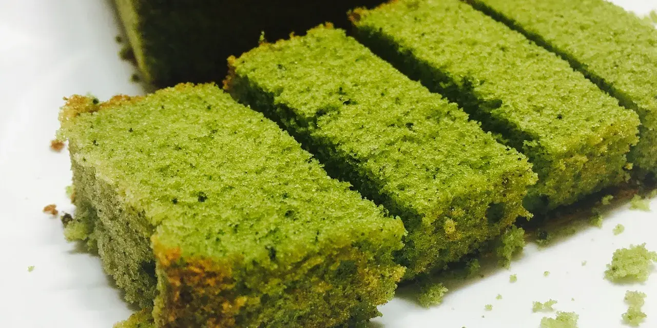 Puszyste ciasto matcha pokrojone w prostokątne kawałki, ułożone na białym talerzu.