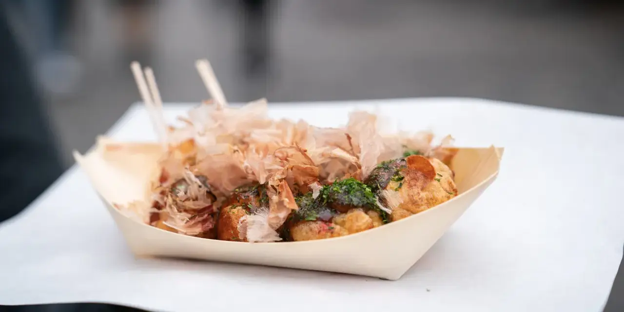 Pyszne takoyaki, czyli japońskie kulki z ośmiornicą, posypane płatkami bonito i zieloną posypką. Idealny japoński street food na wynos.
