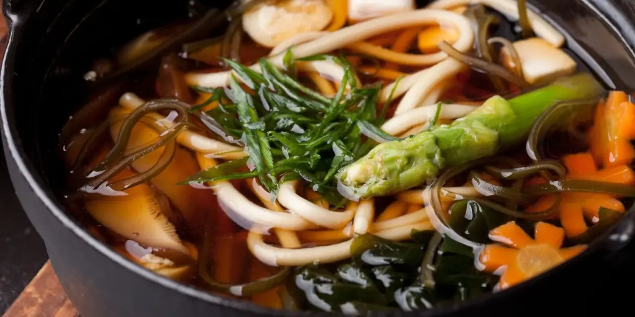 Aksamitny bulion dashi, w którym pływają grube kluski udon, tofu, marchewki w kształcie kwiatków, zielone warzywa i wodorosty. Pyszne i zdrowe danie.