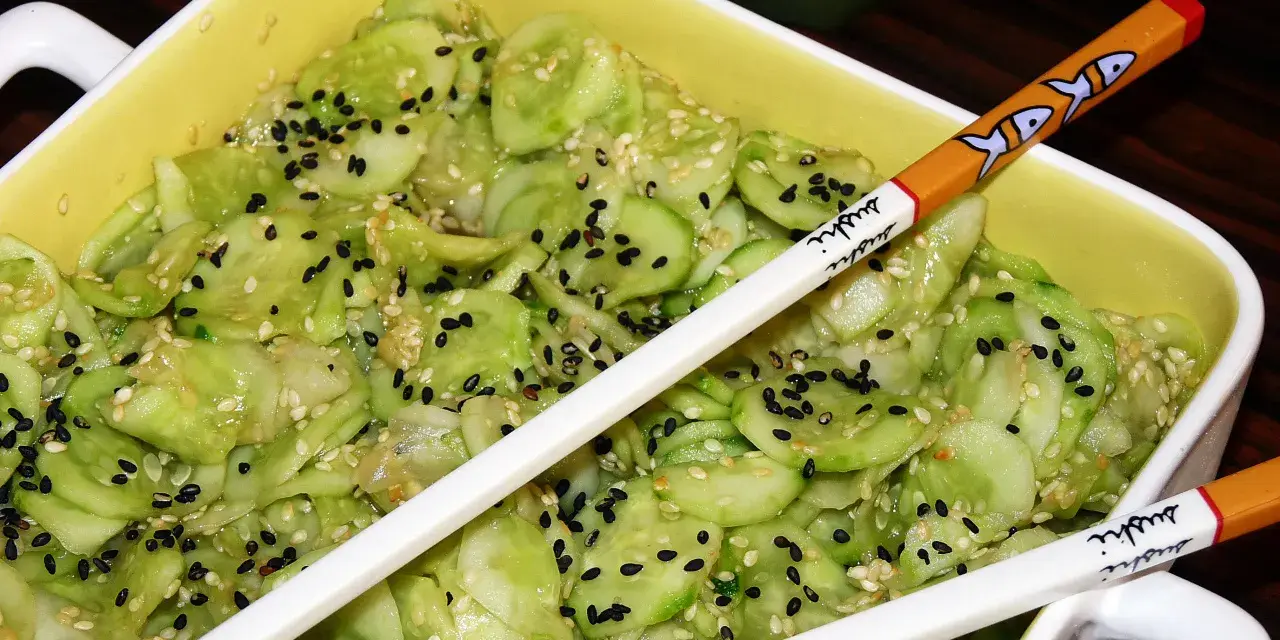 Pyszne ogórki po japońsku, posypane czarnym i białym sezamem, gotowe do jedzenia pałeczkami z motywem sushi.