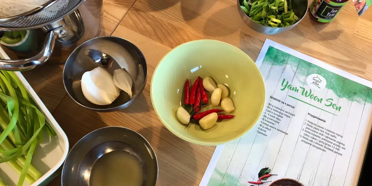 Składniki do zupy **sos tom yum**: czosnek, chili, zielona cebulka, makaron i pasta **sos tom yum** w słoiczku.