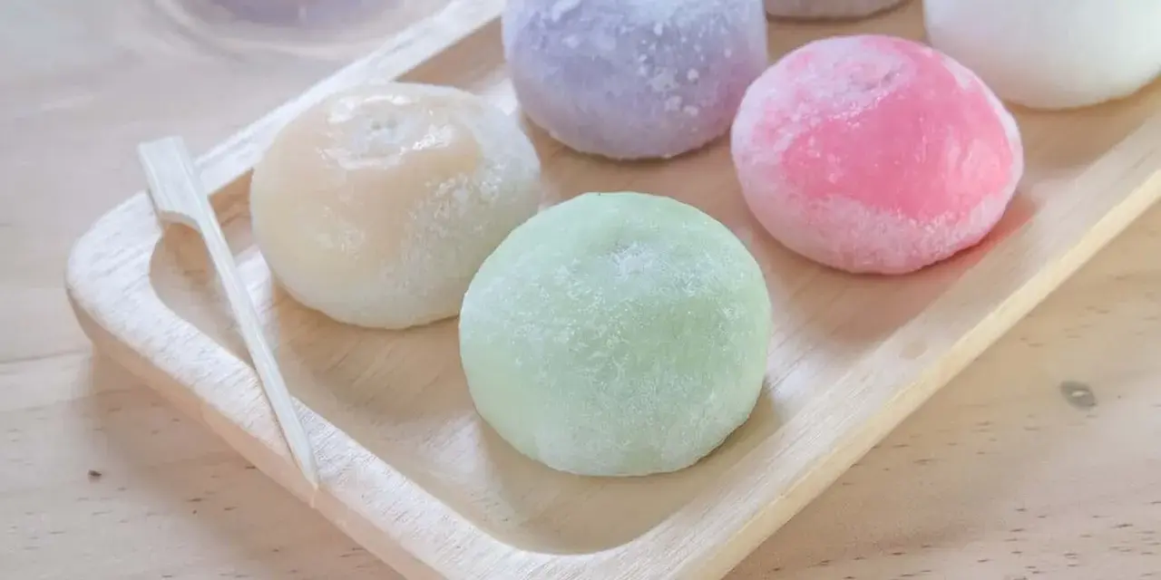 Kolorowe mochi, czyli japońskie ciastka ryżowe, na drewnianej tacy. Zastanawiasz się mochi co to? To pyszna, miękka przekąska!