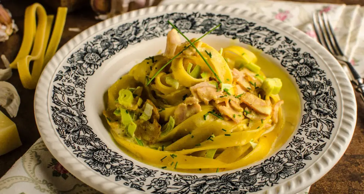 Pyszny makaron curry z kurczakiem i porem w kremowym sosie, ozdobiony szczypiorkiem.