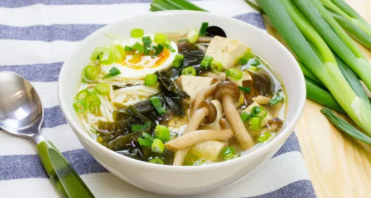 A miska pełna aromatycznej zupy miso z tofu, grzybami, wodorostami, jajkiem i szczypiorkiem.