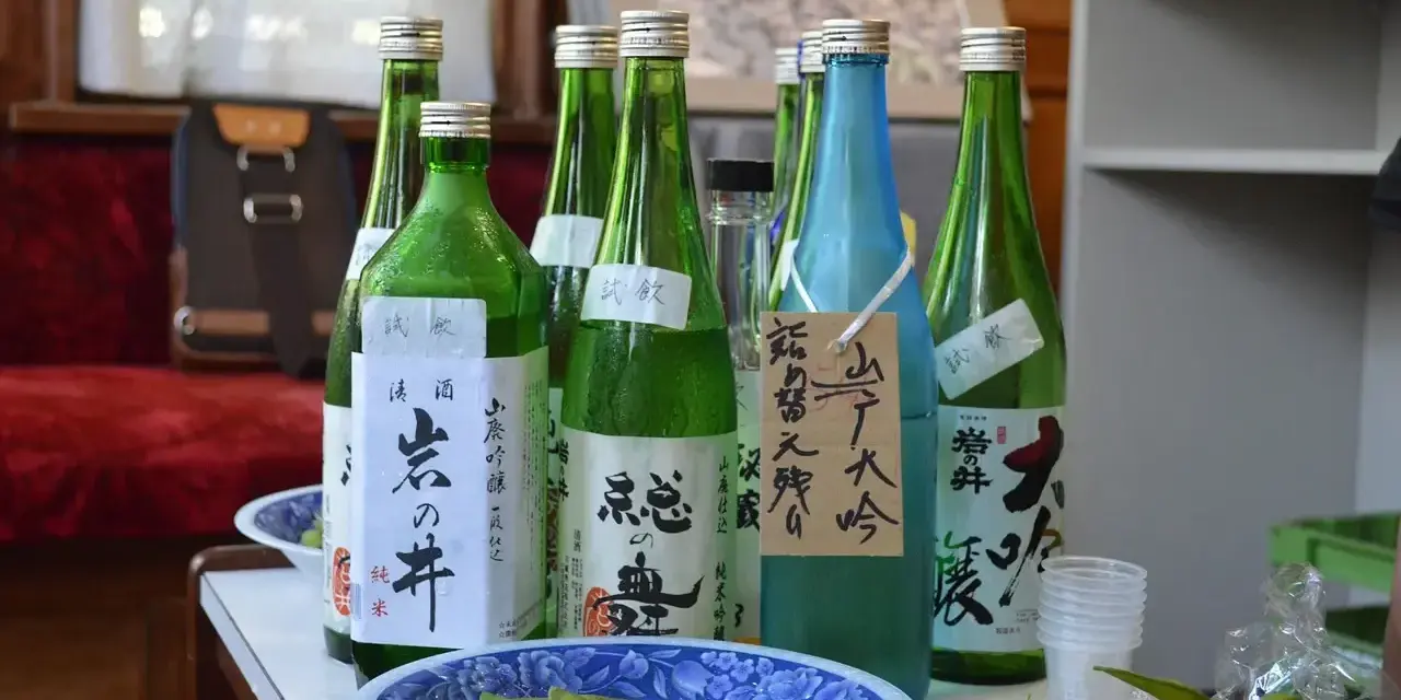 Butelki z japońskim alkoholem, idealne, gdy szukasz, czym zastąpić sake. Obok miseczka z edamame.