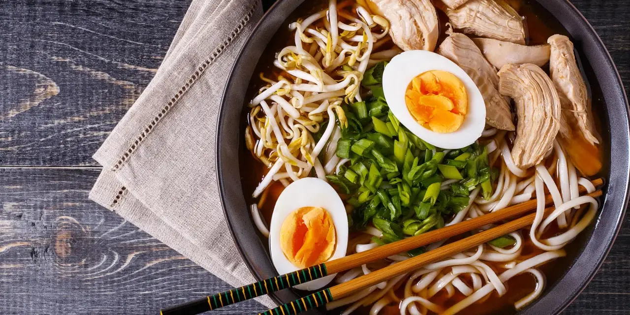 Pyszny shoyu ramen z kurczakiem, jajkiem na twardo, kiełkami fasoli mung i szczypiorkiem.