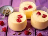 Pyszny jogurt z mango, udekorowany malinami i kardamonem, kusi swoim tropikalnym smakiem.
