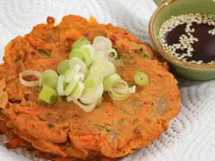 Chrupiące placki z kimchi, posypane szczypiorkiem, obok miseczki z sosem sezamowym. Idealne na przekąskę.