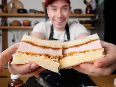 Uśmiechnięty mężczyzna prezentuje pyszne katsu sando z soczystym kotletem schabowym w panierce, delikatną kapustą i puszystym chlebem.