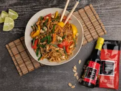 Kolorowy makaron wok z warzywami i orzeszkami ziemnymi, podany z sosami House of Asia.