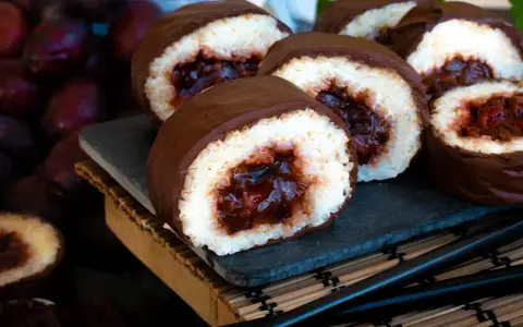 Słodkie rolki sushi na słodko, oblane czekoladą, z owocowym nadzieniem. Obok ciemne owoce i pałeczki.