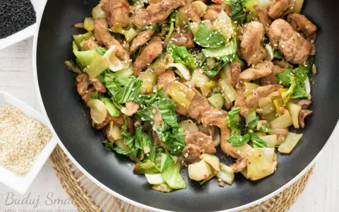 Smażony kurczak z pak choi, posypany sezamem, gotowy do podania.