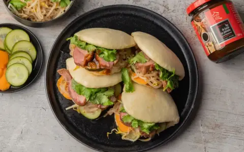 Bao z kaczką w 5 smakach, z kiełkami, kolendrą i warzywami. Obok sos do kaczki.