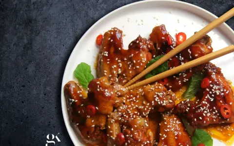 Pyszne skrzydełka teriyaki, błyszczące od sosu, posypane sezamem i ozdobione plasterkami chili.