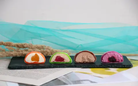 Cztery kolorowe mochi: pomarańczowe, zielone z malinami, czekoladowe i fioletowe z jagodami. Różne rodzaje słodkości.