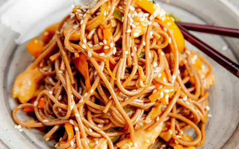 Soba z kurczakiem i warzywami, posypana sezamem. Pyszny przepis na soba, idealny na szybki obiad.