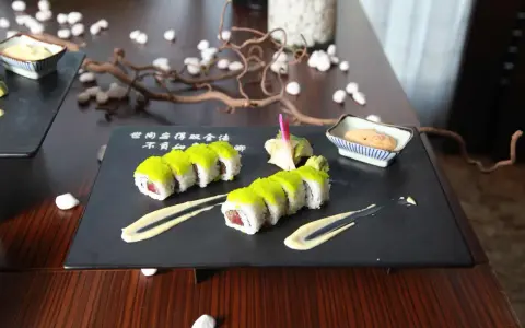 Dwa rzędy sushi z zielonym ikrą, podane z sosem i imbirem. Idealny sposób, jak podawać sushi na eleganckim talerzu.
