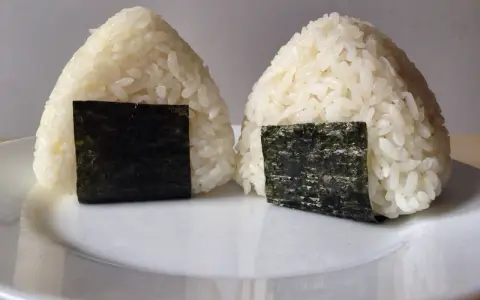 Dwa ryżowe onigiri z nori, gotowe do spożycia. Idealne nadzienie do onigiri sprawia, że są pyszne.