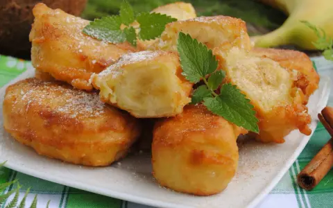 Słodki banan w cieście kokosowym, posypany cukrem pudrem i cynamonem, z listkami mięty. Idealny deser.