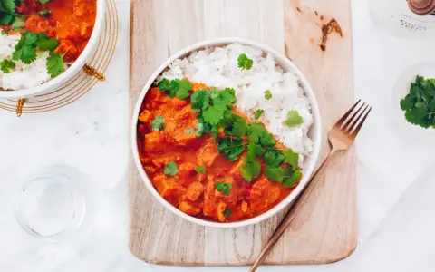 Aksamitny kurczak w czerwonym curry, podany z ryżem i świeżą kolendrą. Idealny na rozgrzewający posiłek.