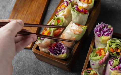 Chwytam pałeczkami świeże sajgonki z krewetkami, czerwoną kapustą i warzywami. Idealne co do sushi!