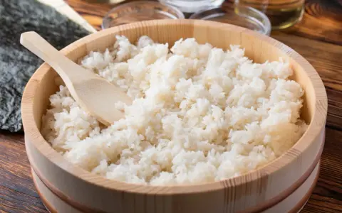 Gotowy do sushi ryż w drewnianym naczyniu, obok nori i składników. Różne rodzaje ryżu do sushi są kluczowe.