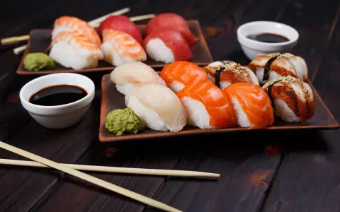 Wyśmienite japońskie sushi: nigiri z łososiem, rybą maślaną i krewetką, podane z wasabi i sosem sojowym.