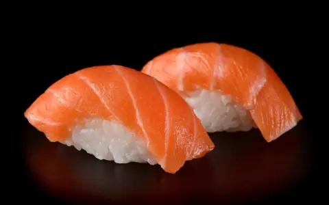 Dwa kawałki sushi z łososiem, idealna ryba do sushi, na czarnym tle.
