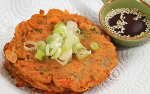 Chrupiące placki z kimchi, posypane szczypiorkiem, obok miseczki z sosem sezamowym. Idealne na przekąskę.