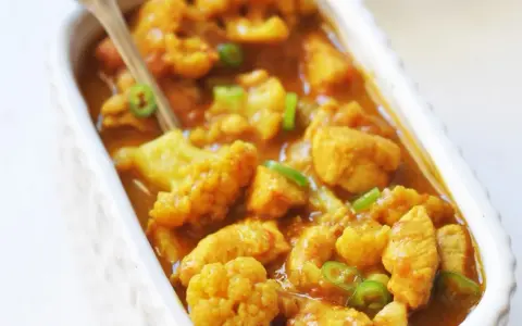 Aromatyczne curry z kurczakiem i kalafiorem w kremowym sosie, posypane zieloną papryczką chili.