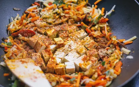Smażone warzywa po chińsku z tofu i ryżem, doprawione kurkumą i papryką, gotowe do podania.
