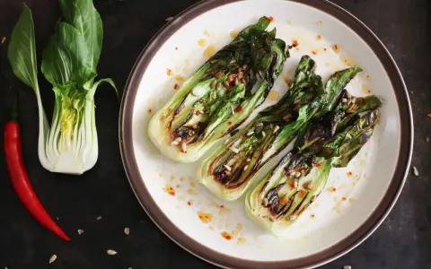 Grillowany pak choi z nasionami słonecznika i papryczką chili na talerzu.
