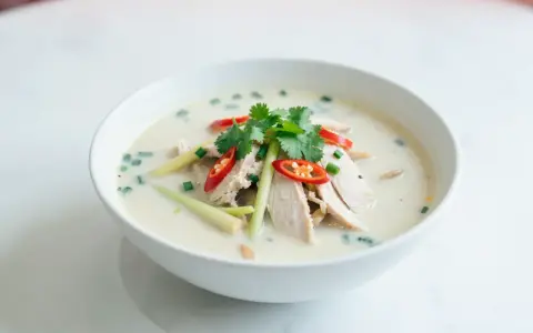 Aromaticzna zupa tom kha z kurczakiem, ozdobiona kolendrą, chili i trawą cytrynową.