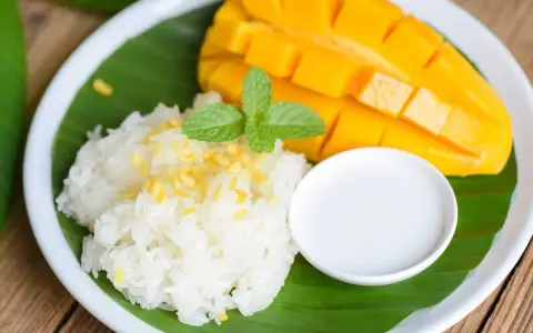 Pyszny mango sticky rice: ryż kleisty z kawałkami mango, polany mleczkiem kokosowym, udekorowany miętą.