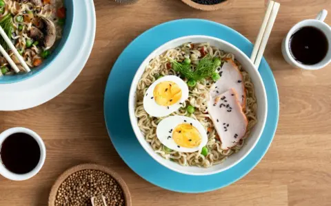 Pyszny tantanmen ramen z jajkiem, plastrami mięsa i zielonym groszkiem. Idealny na szybki, sycący posiłek.