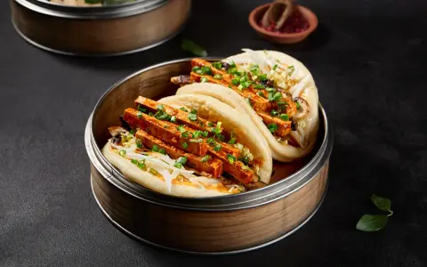 Pierożki baozi z tofu i warzywami, podane w bambusowym parowniku.