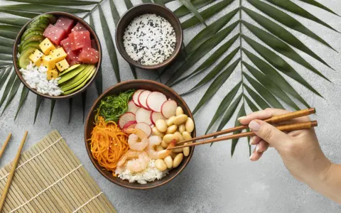 Dwie miski z pysznym sushi: jedna z tuńczykiem, awokado i ogórkiem, druga z krewetkami, fasolką i warzywami.